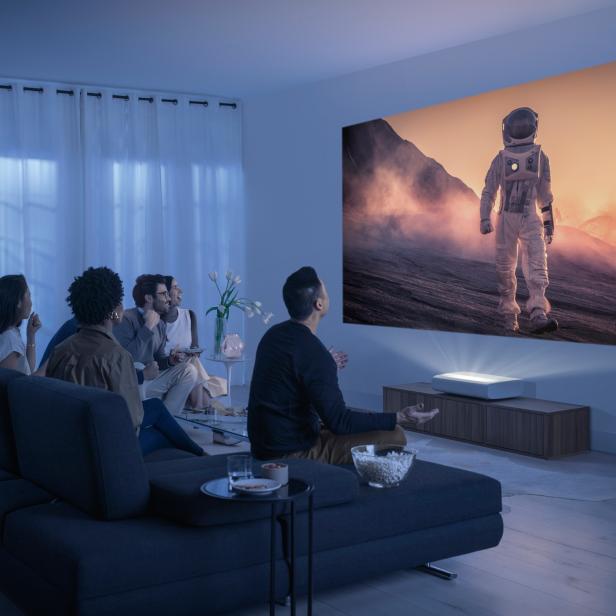 Eine Gruppe von Leuten schaut einen Film mit einem Astronauten auf einer Leinwand.