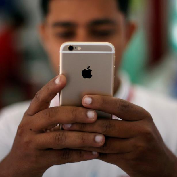 FILE PHOTO: A salesman checks a customer's iPhone at a mobile phone store in New Delhi