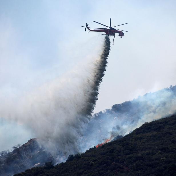 A helicopter makes a water drop over a wildfire in the Angeles National Forest during the Bobcat Fire in Los Angeles