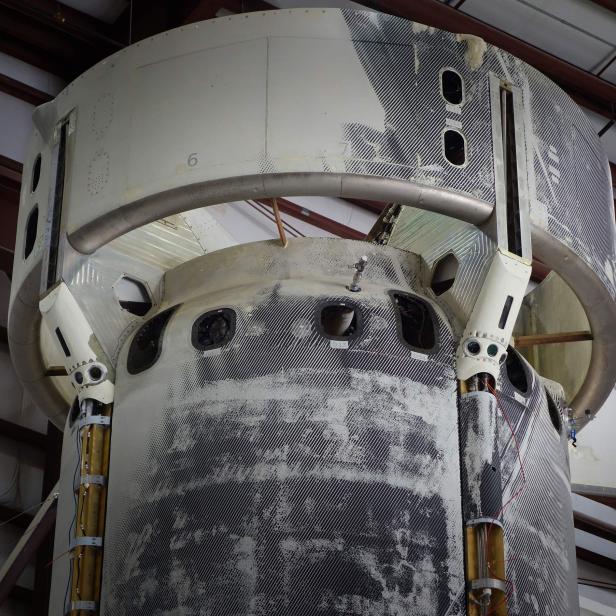 Ein teilweise demontiertes Raumschiffteil in einer Werkshalle.