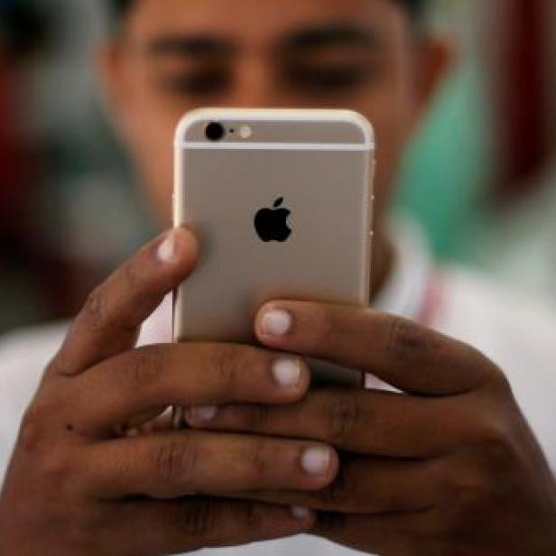 Eine Person hält ein goldenes iPhone in den Händen.