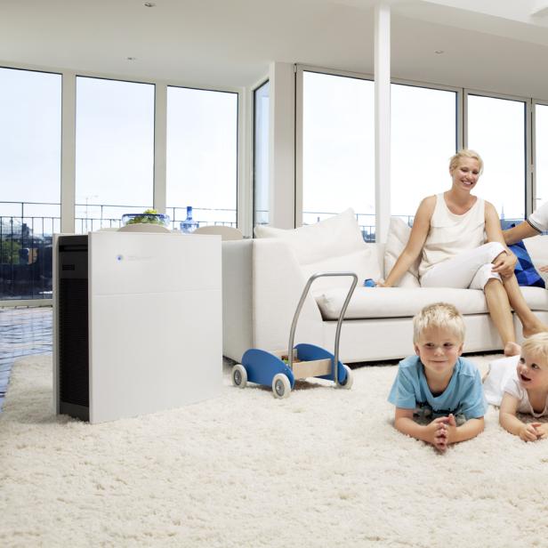 Eine Familie entspannt sich in einem hellen Wohnzimmer mit einem Luftreiniger.