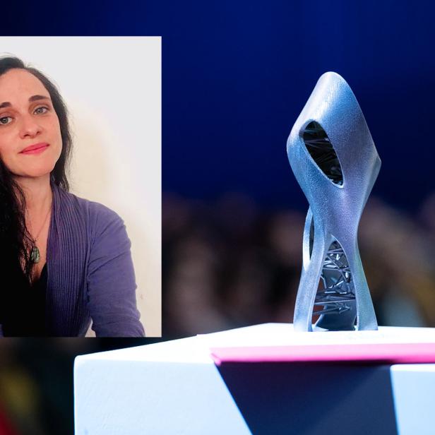 Eine Frau und eine moderne Skulptur auf einem Sockel vor einem Publikum.