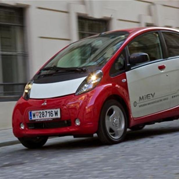 Ein rot-weißer Mitsubishi i-MiEV fährt auf einer Straße.