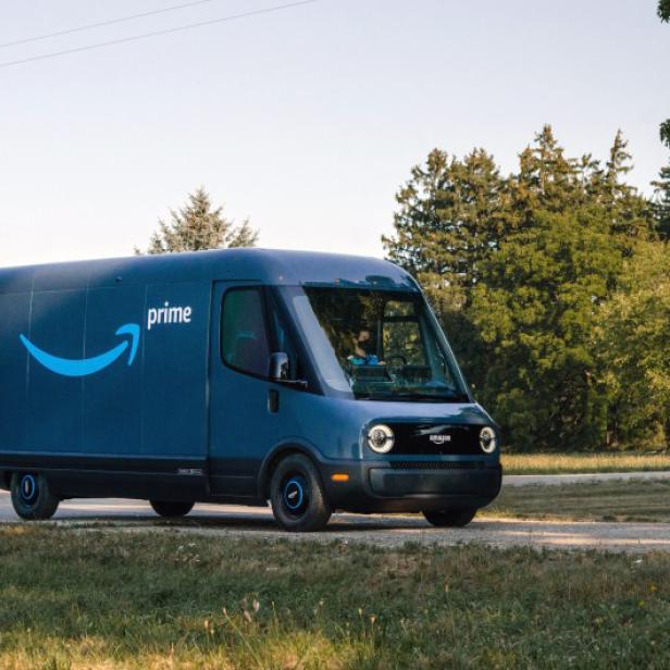 Ein blauer Amazon Prime Lieferwagen fährt auf einer Landstraße.