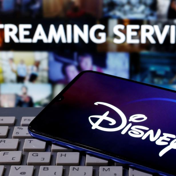 FILE PHOTO: Smartphone with displayed "Disney" logo is seen on the keyboard in front of displayed "Streaming service" words in this illustration