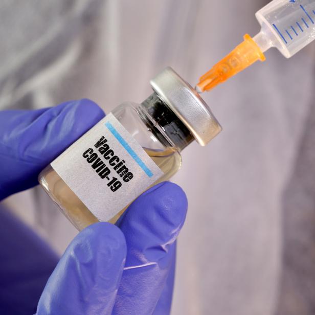 FILE PHOTO: A woman holds a small bottle labeled with a "Vaccine COVID-19" sticker and a medical syringe in this illustration