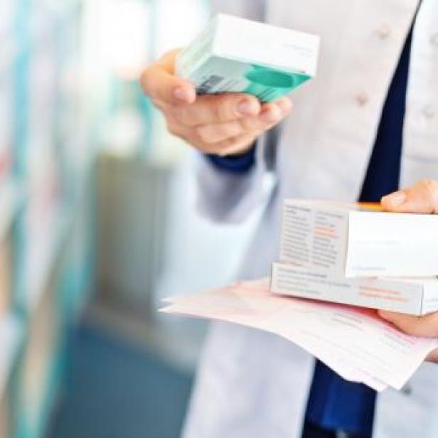 Ein Apotheker hält Medikamentenpackungen in der Hand.