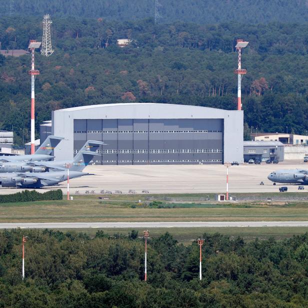 Mehrere US Air Force C-17 Globemaster III Flugzeuge stehen auf einem Flugfeld vor einem Hangar.