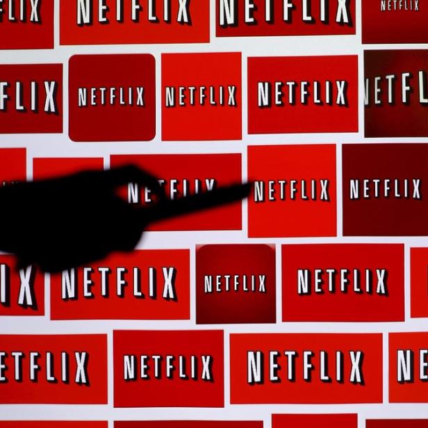 Das Netflix-Logo ist mehrfach auf einer Wand abgebildet, wobei ein Schatten auf eines der Logos fällt.