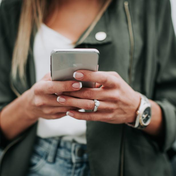 Woman hand typing in the mobile outside