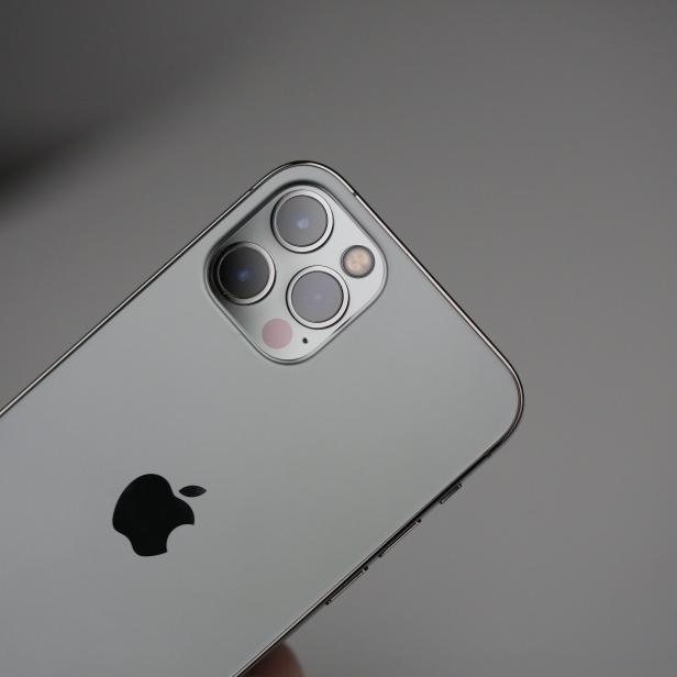 Die Rückseite eines grauen iPhones mit drei Kameras und dem Apple-Logo.