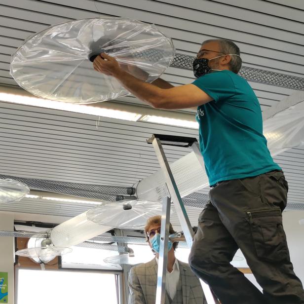 Ein Mann auf einer Leiter montiert eine transparente Abdeckung an der Decke.