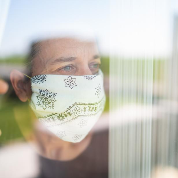 mature adult woman with mouse nose mask looking out through the window