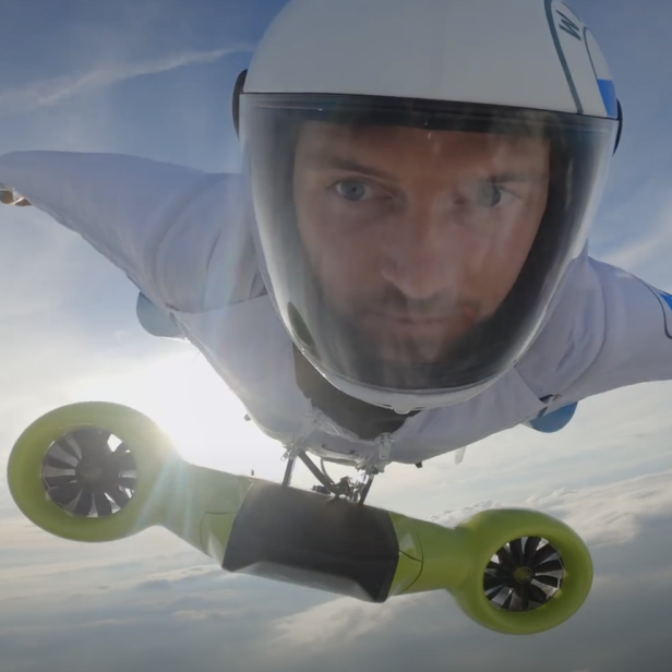 Ein Mann fliegt mit einem Raketenrucksack vor blauem Himmel.
