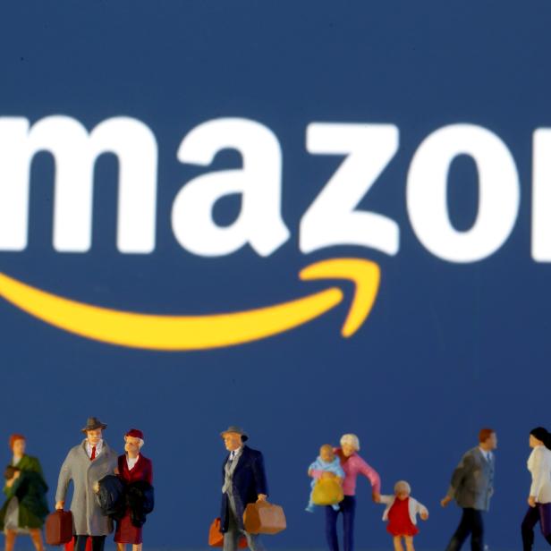 FILE PHOTO: FILE PHOTO: Small toy figures are seen in front of diplayed Amazon logo