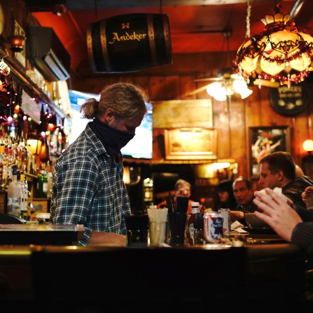 A bartender wearing a facial covering works while people drink and socialize as the coronavirus disease (COVID-19) outbreak continues in Milwaukee
