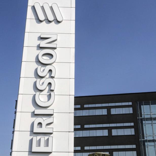 Das Ericsson-Logo vor einem modernen Bürogebäude unter blauem Himmel.