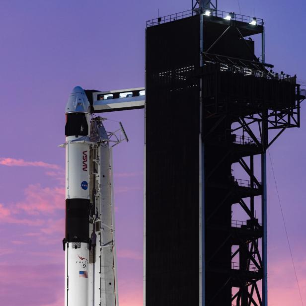 Eine Falcon 9 Rakete steht auf einer Startrampe der NASA vor einem lila Himmel.