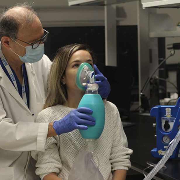 Ein Arzt mit Maske beatmet eine Patientin mit einem Beatmungsbeutel.