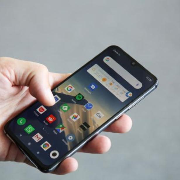 Eine Hand hält ein Smartphone mit verschiedenen App-Symbolen auf dem Bildschirm.
