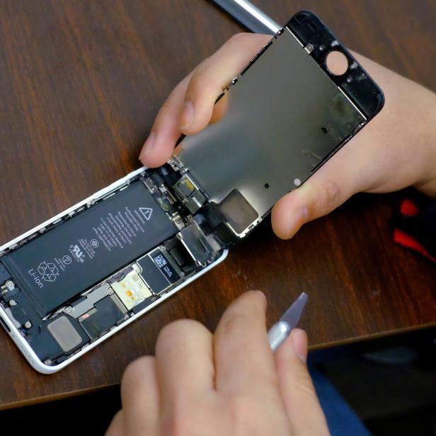 FILE PHOTO: A man tries to repair an iPhone in a repair store in New York