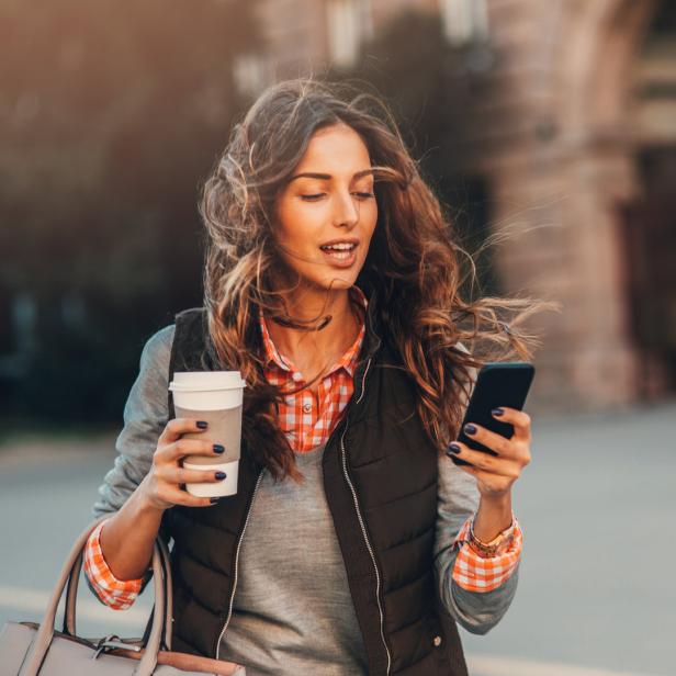 Frau mit Handy und Kaffee