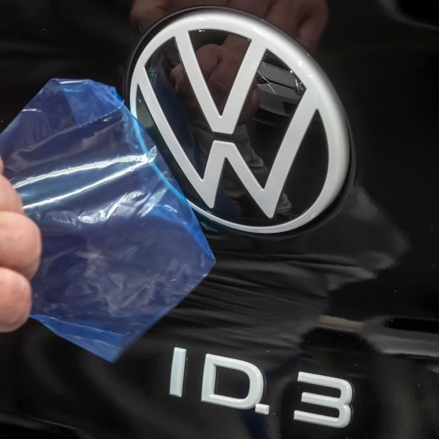 Ein Volkswagen ID.3-Emblem wird von einer blauen Schutzfolie befreit.
