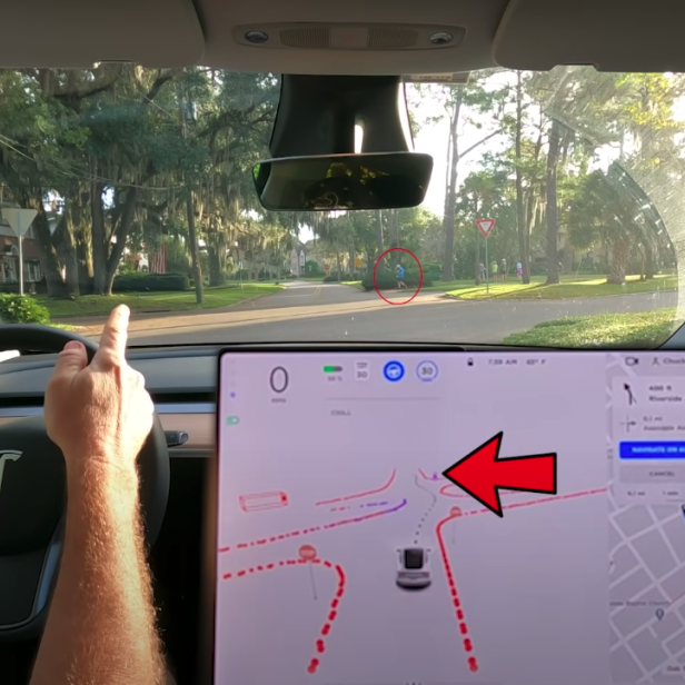 Ein Tesla nähert sich einer Kreuzung mit einem Fußgänger.