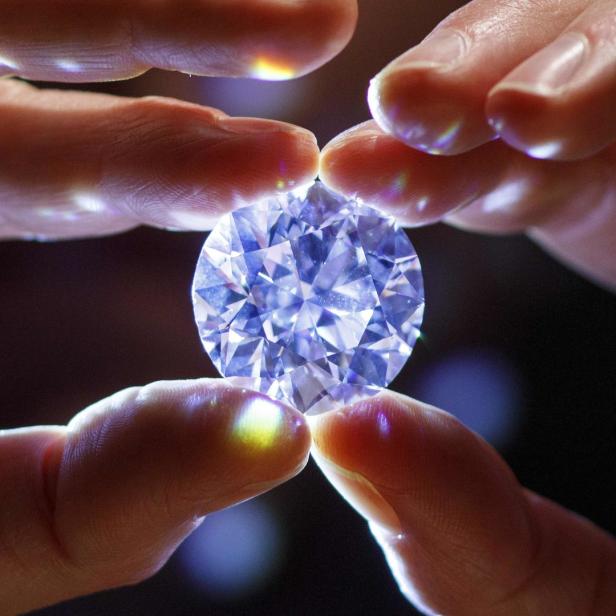 Ein großer, lupenreiner Diamant wird von zwei Fingern gehalten.