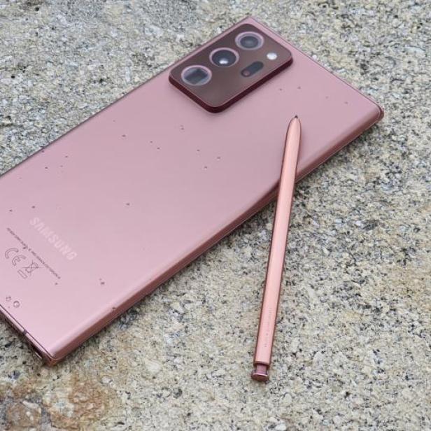 Ein rosafarbenes Samsung-Smartphone mit Stift liegt auf einer rauen Oberfläche.