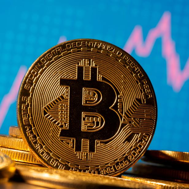 FILE PHOTO: A representation of virtual currency Bitcoin is seen in front of a stock graph