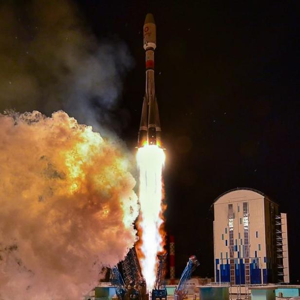 Eine Rakete startet bei Nacht mit einer großen Rauchwolke.