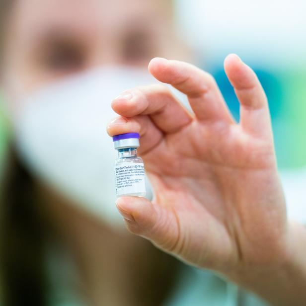 Eine Hand hält ein Fläschchen des Pfizer-BioNTech COVID-19-Impfstoffs.