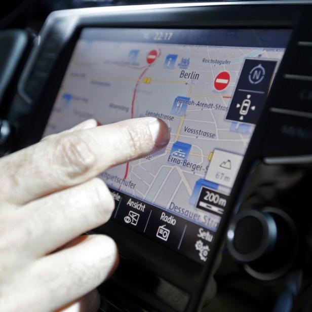 Ein Mann tippt auf den Bildschirm eines Navigationssystems, das eine Karte von Berlin anzeigt.