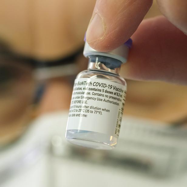 Eine Hand hält eine Durchstechflasche des Pfizer-BioNTech COVID-19-Impfstoffs.