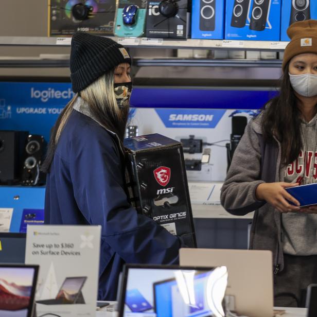 Zwei Frauen mit Gesichtsmasken kaufen Elektronik in einem Geschäft ein.