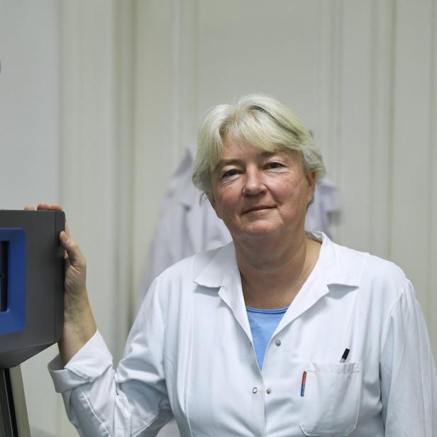 Eine Frau in einem Laborkittel steht neben einem Gerät.