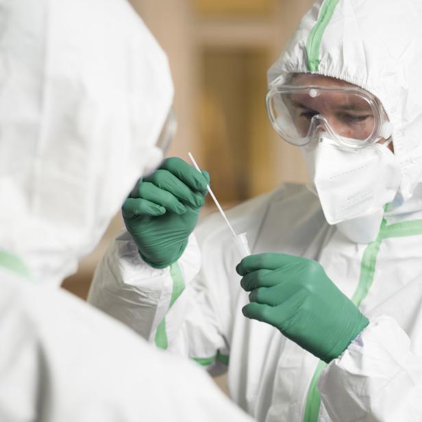 Zwei Personen in Schutzkleidung führen einen Corona-Test durch.