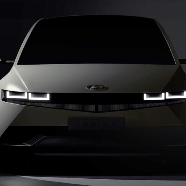 Die Frontansicht eines Hyundai IONIQ 5 mit eingeschalteten Scheinwerfern.