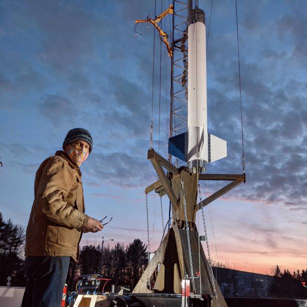 Ein Mann steht vor einer Rakete, die auf einem Anhänger montiert ist.