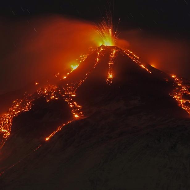 An eruption from Mount Etna lights up the sky during the night, seen from Fornazzo