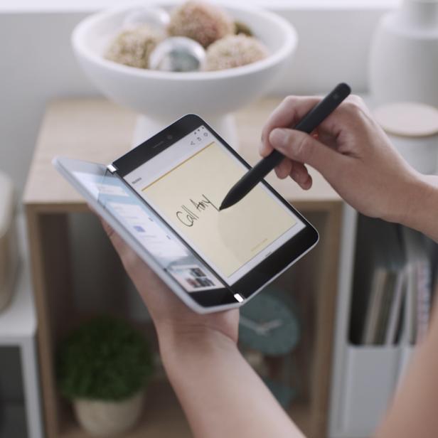 Eine Person schreibt mit einem Stift auf einem zusammenklappbaren Tablet „Call Amy“.