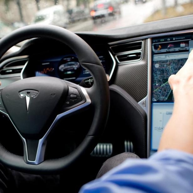 Ein Fahrer bedient den Touchscreen eines Tesla-Autos.