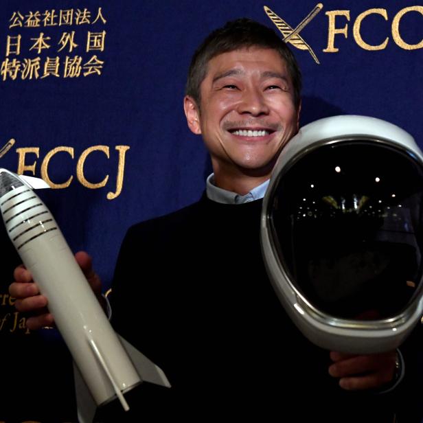 Der japanische Unternehmer Yusaku Maezawa mit einem Spielzeugraumschiff und einem Helm vor einem FCCJ-Hintergrund.