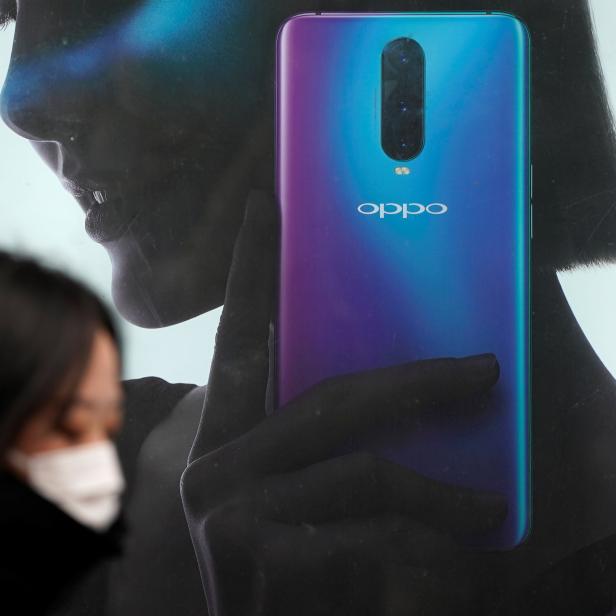 A woman walks past an Oppo advertisement at a shopping mall in Shanghai