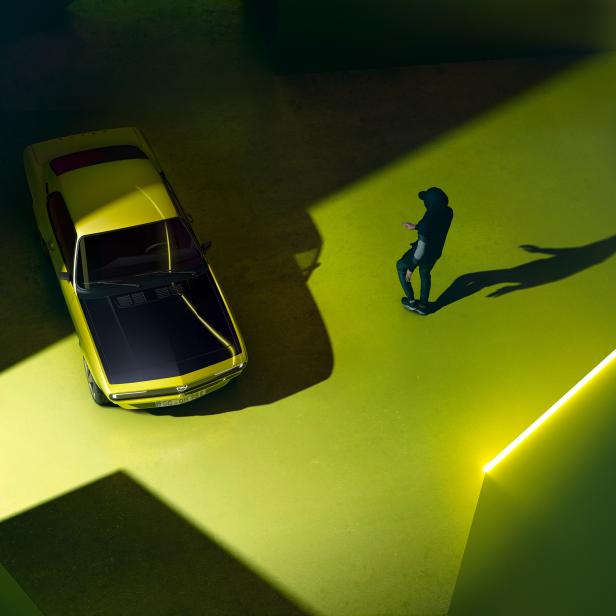 Ein gelber Opel Manta steht in einem Raum mit einer Person im Schatten.