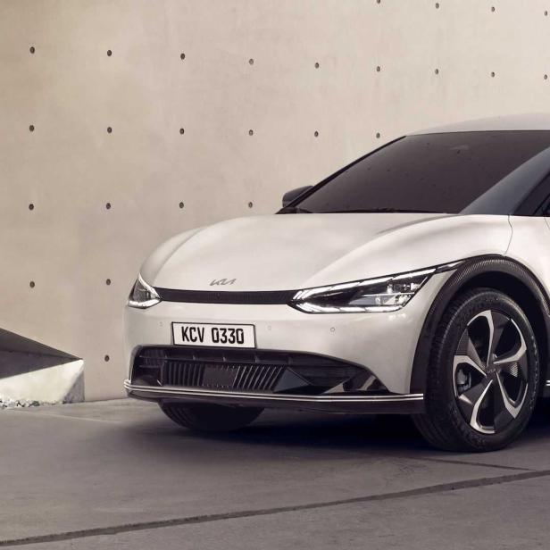 Ein weißer Kia EV6 geparkt vor einem modernen Gebäude.