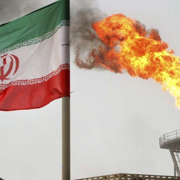 Die iranische Flagge weht vor einer Feuerfackel und einer Ölförderanlage.