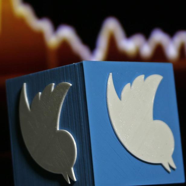 Ein blaues Quadrat mit dem Twitter-Logo vor einem unscharfen Diagramm.